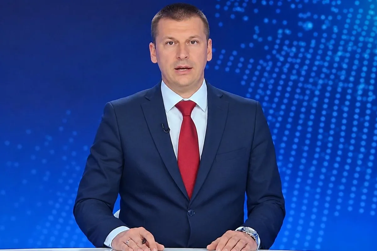 Mavi stüdyoda kırmızı kravatlı erkek haber spikeri, seçim sonrası gelişmeleri ekrana taşıyor.